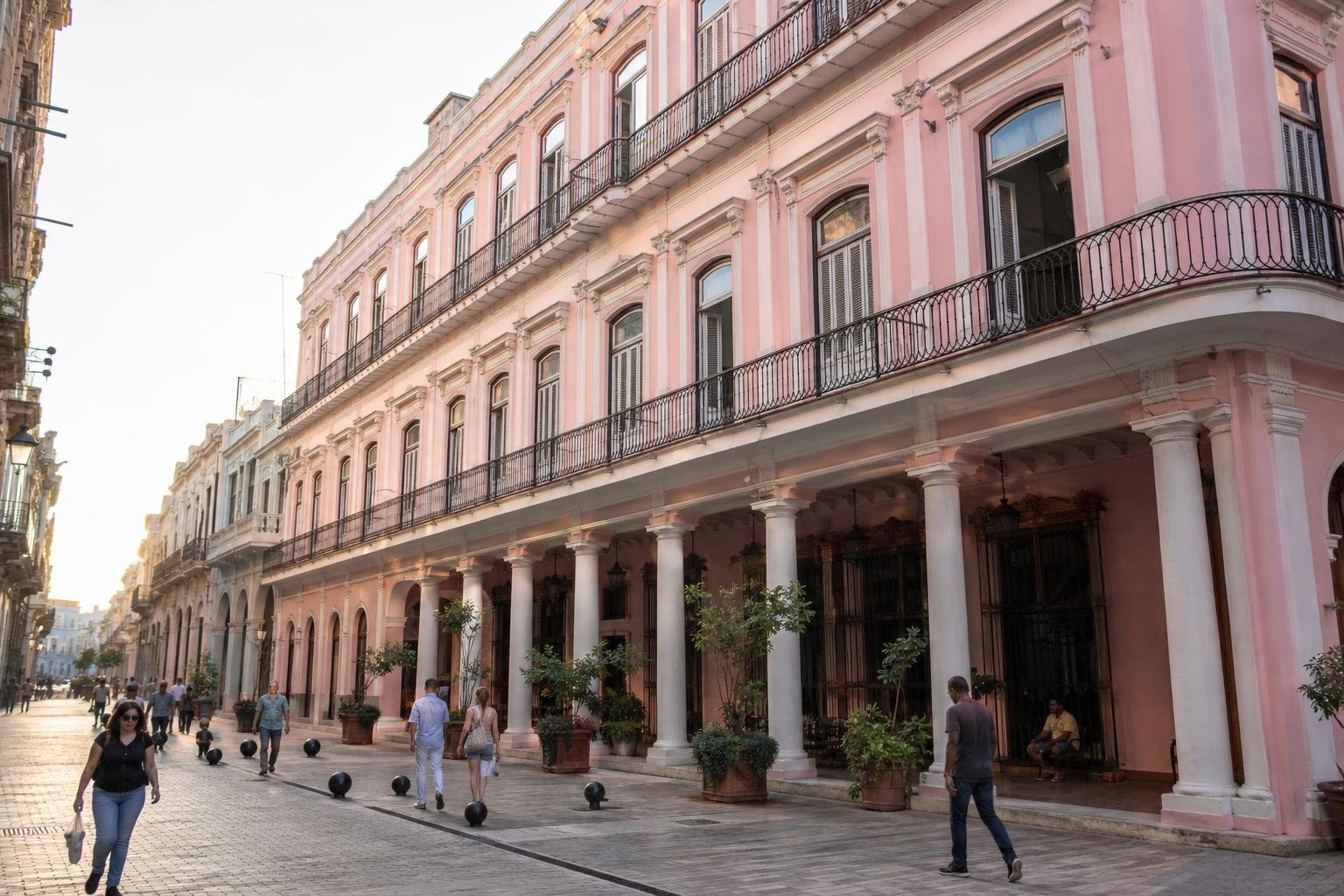Pink Hotel Ambos Mundos façade with rows of windows above pedestrians on a narrow Old Havana street.